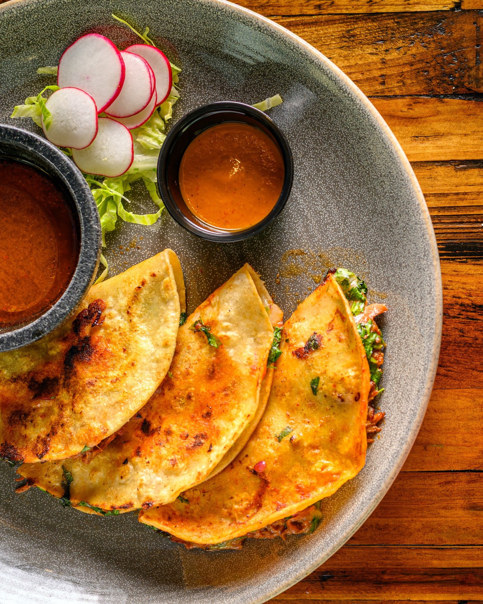 Quesabirrias served with consommé, salsa, and sliced radishes